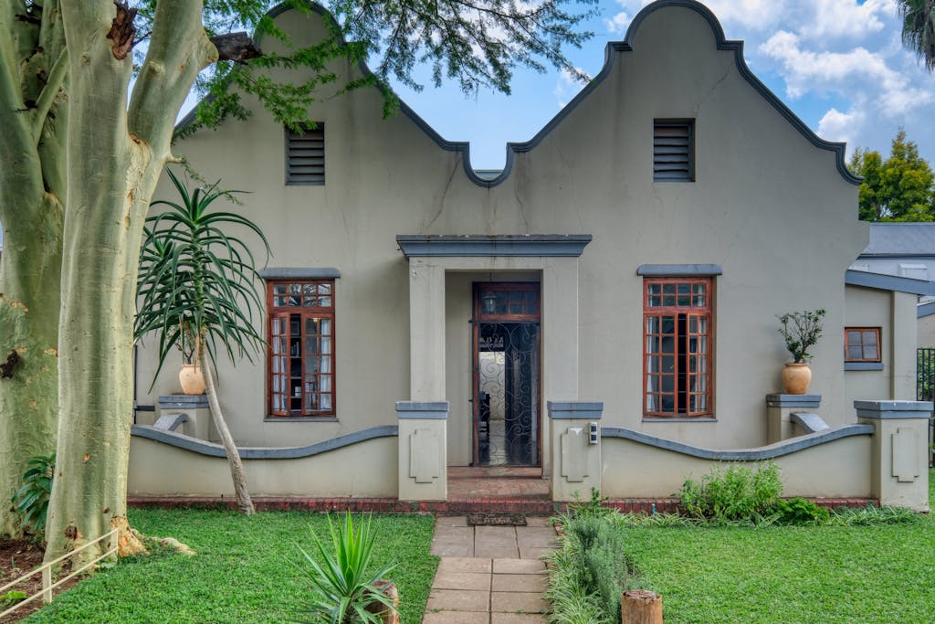Front view of a charming historic house with unique architectural design and a lush garden.